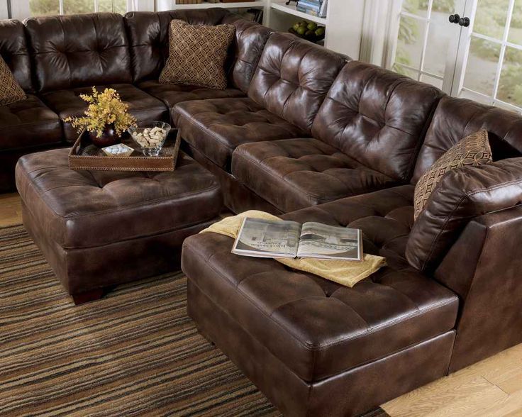 This may contain: a living room with brown leather furniture in it