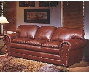 This may contain: a brown leather couch sitting in a living room next to a lamp and window with blinds